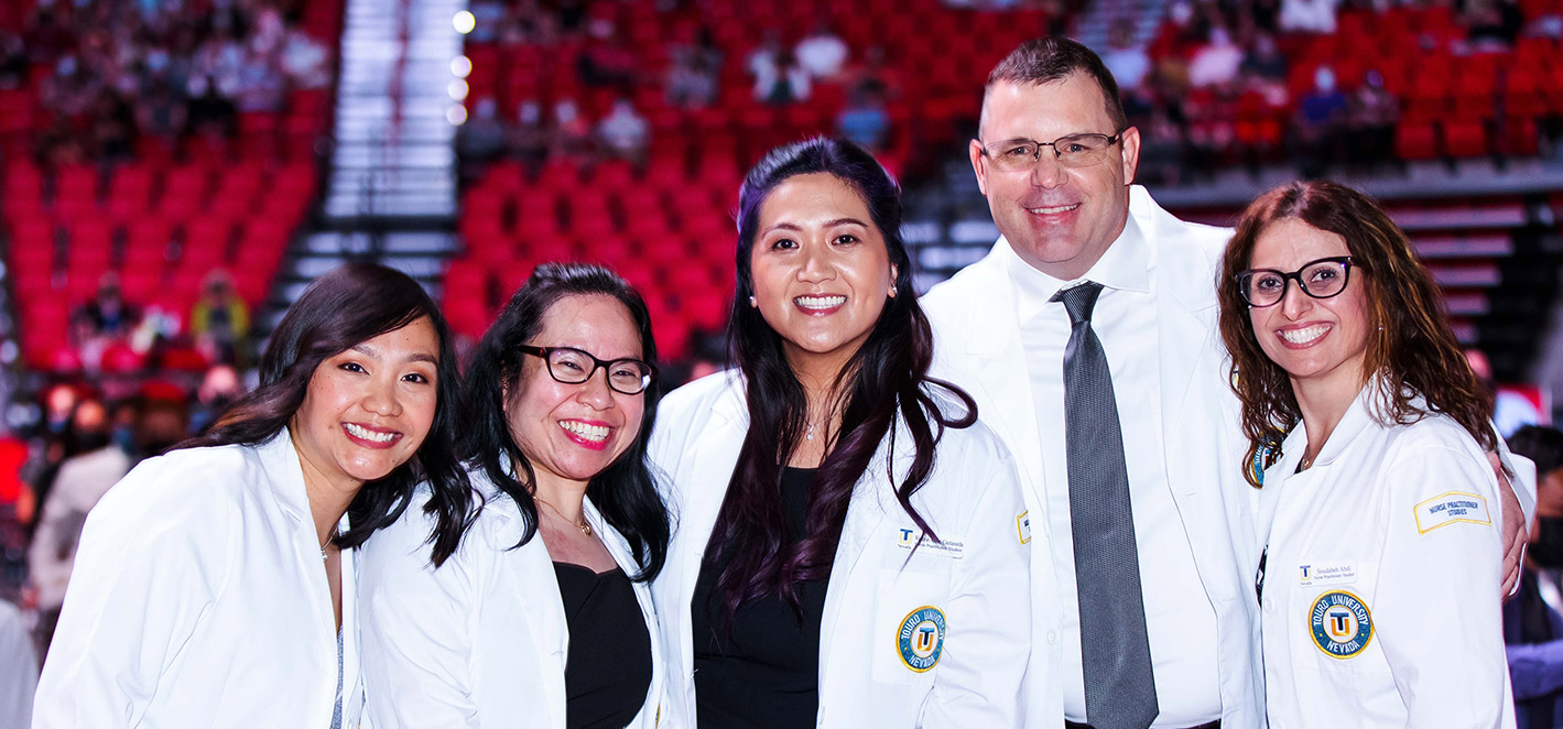 CHHS students smile at the camera in their white coats.