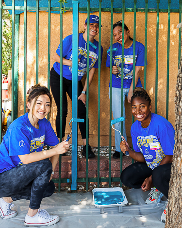 Students painting a fence at Opportunity Village