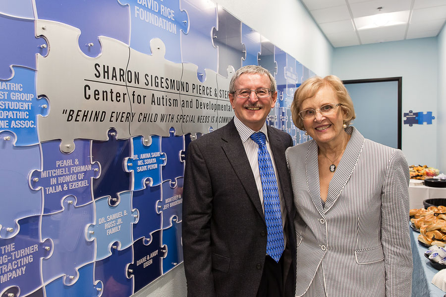 Sharon Sigesmund Pierce and Stephen Pierce stand in front of the Autism Center sign