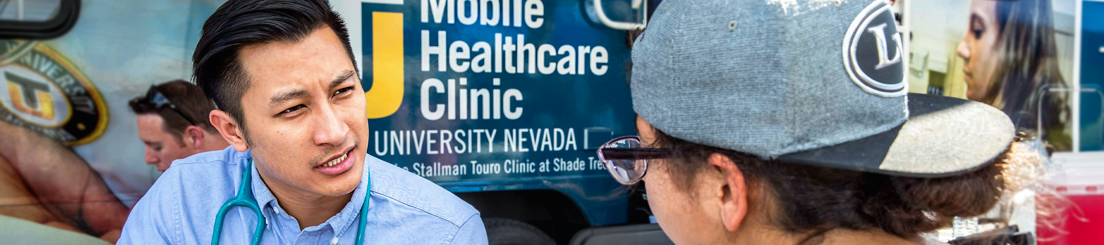 A student speaking with a patient in front of the mobile clinic.