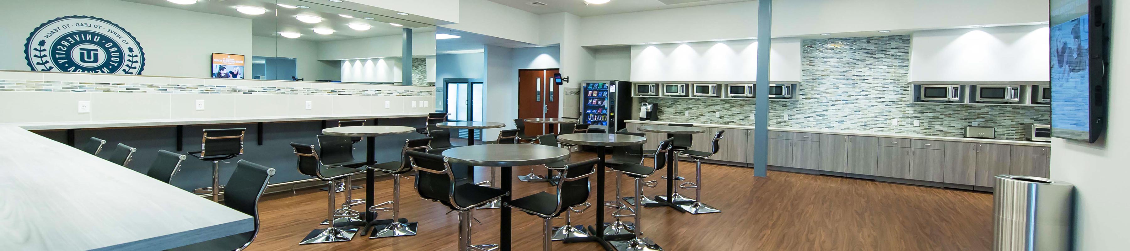 Student Common Area with tables, chairs, and food prep area with vending machine and microwave.