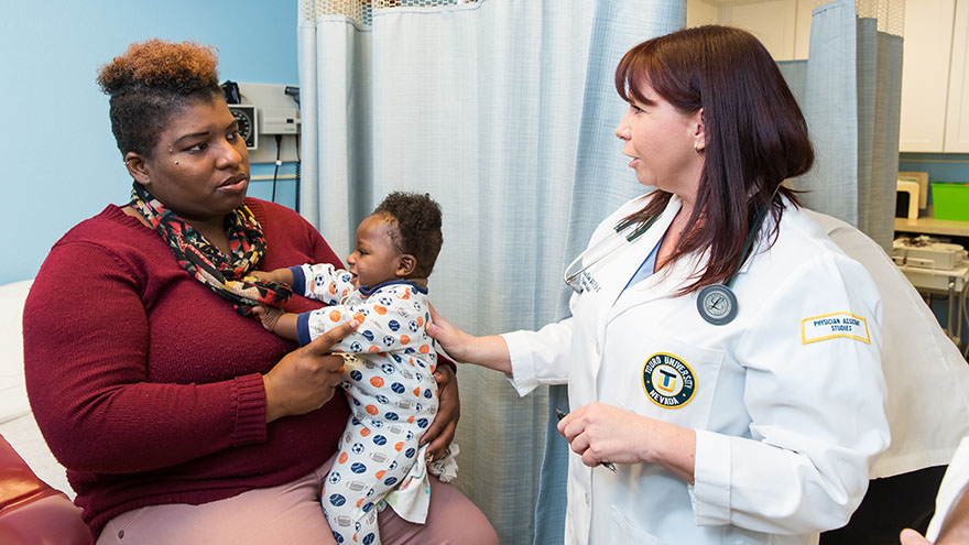 A student talks to a woman and her child in a clinic. 