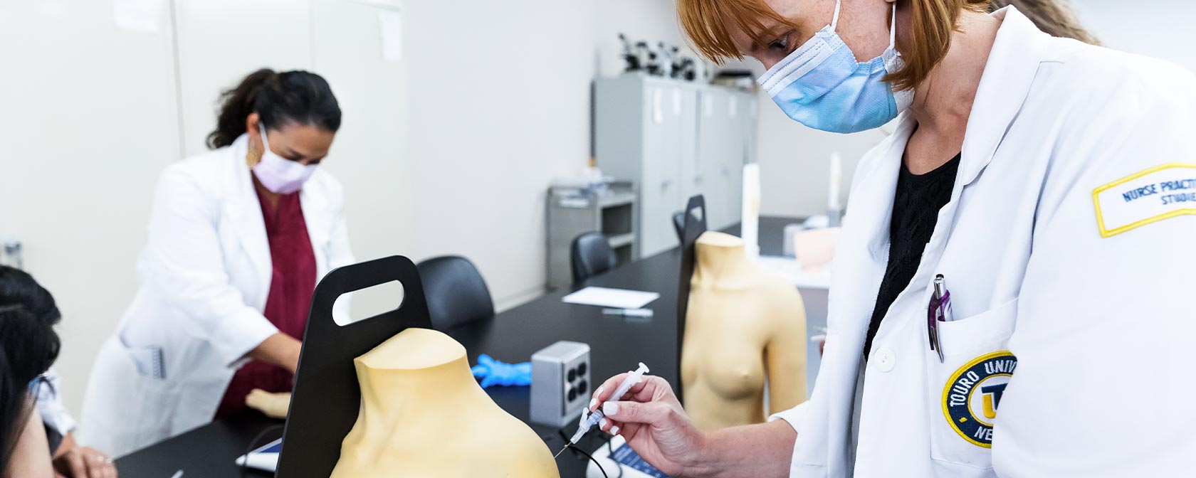 Touro nursing students practice administering shots on mannequins during their on-campus labs.