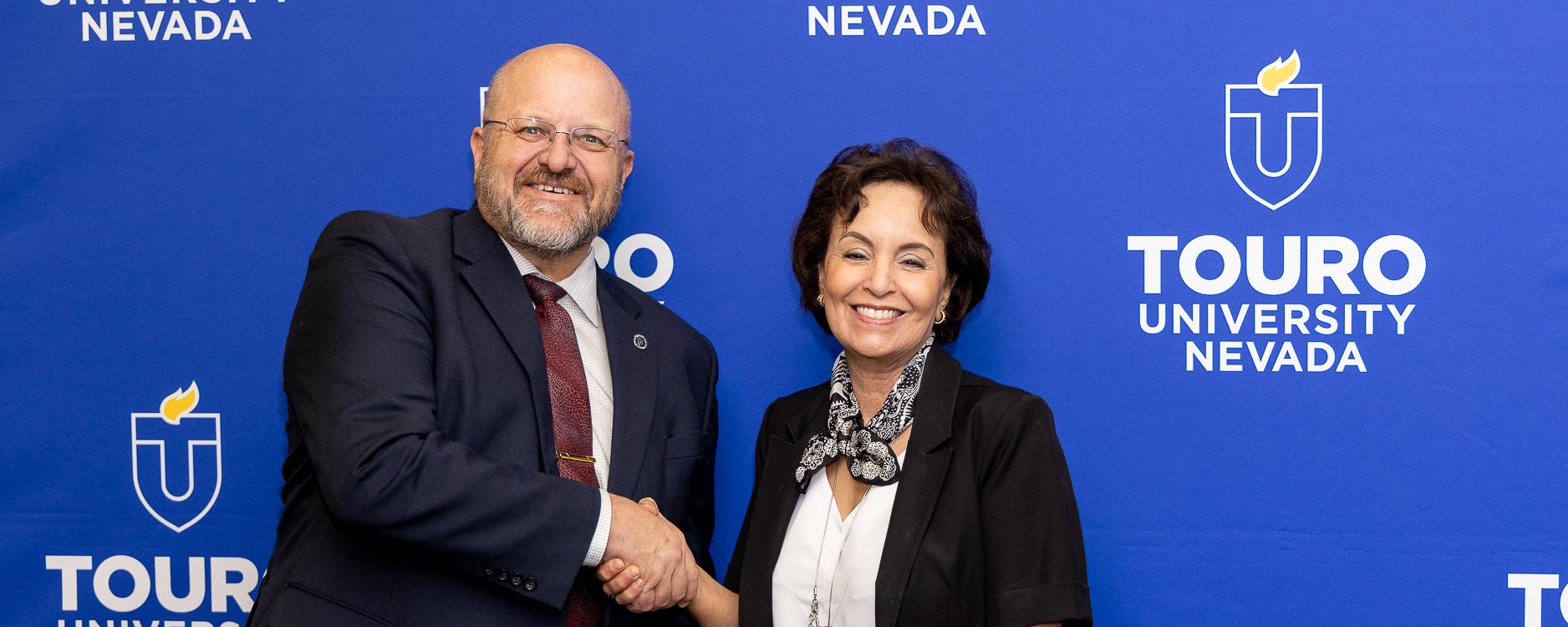 Dr. Andrew Priest offers a congratulatory handshake to faculty member, Dr. Amina Sadik, for 20 years at Touro Nevada.