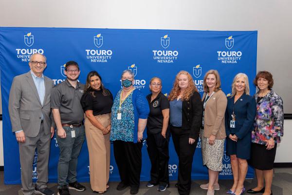 University leadership takes a group photo with the ten-year faculty and staff during the 2025 employee recognition event in front of the Touro University Nevada logo.
