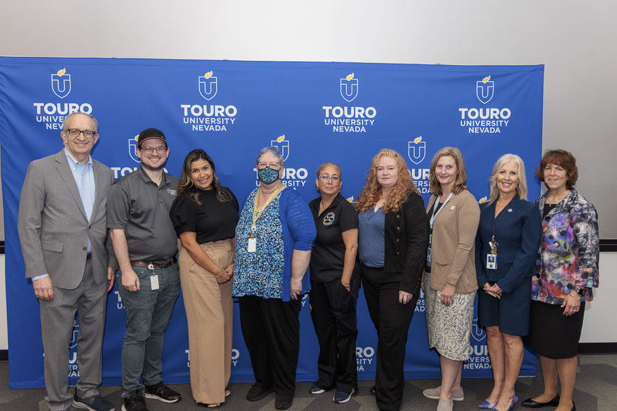 University leadership takes a group photo with the ten-year faculty and staff during the 2025 employee recognition event in front of the Touro University Nevada logo.