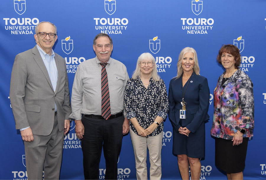 University leadership takes a group photo with the fifteen-year faculty and staff during the 2025 employee recognition event in front of the Touro University Nevada logo.