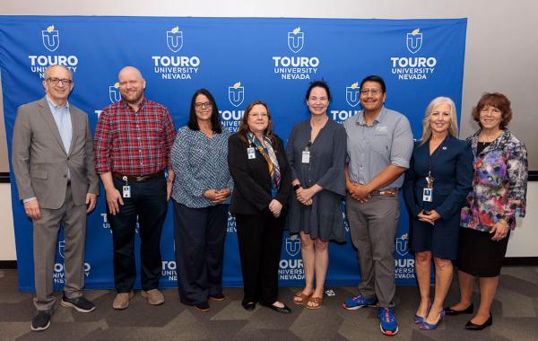 University leadership takes a group photo with the five-year faculty and staff during the 2025 employee recognition event in front of the Touro University Nevada logo.