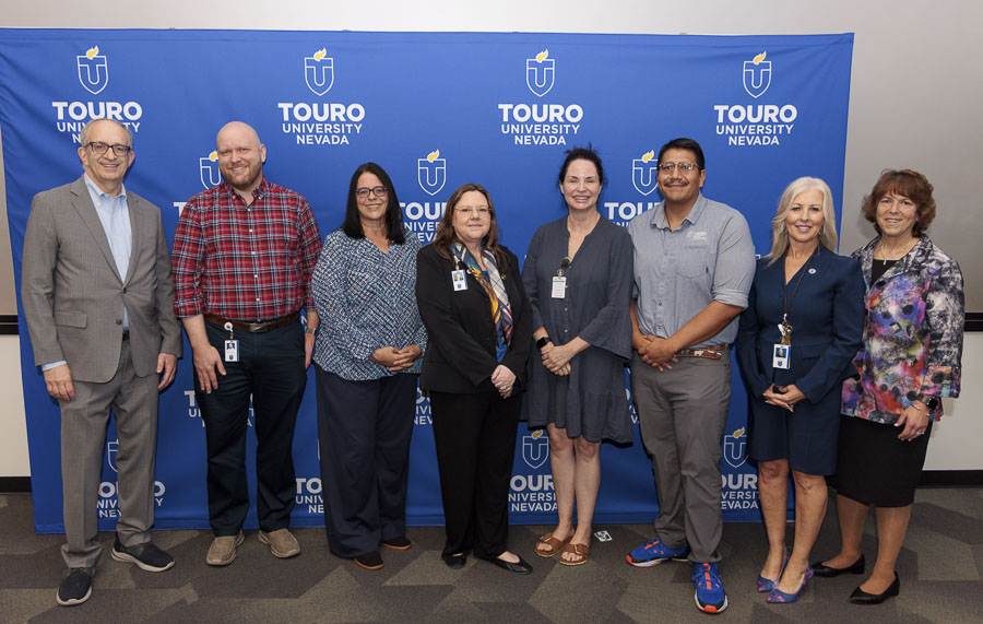 University leadership takes a group photo with the five-year faculty and staff during the 2025 employee recognition event in front of the Touro University Nevada logo.