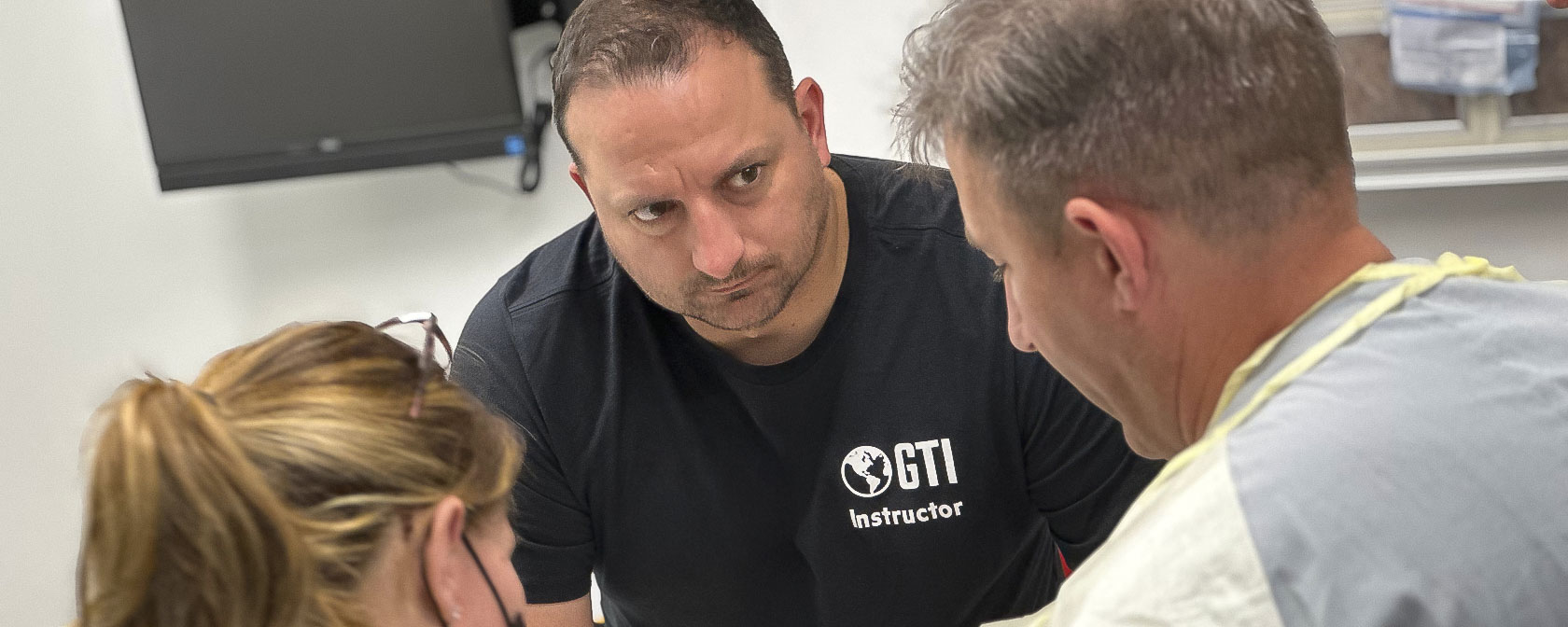 A GTI instructor works with two attendees during the advanced trauma training session in the simulation center.